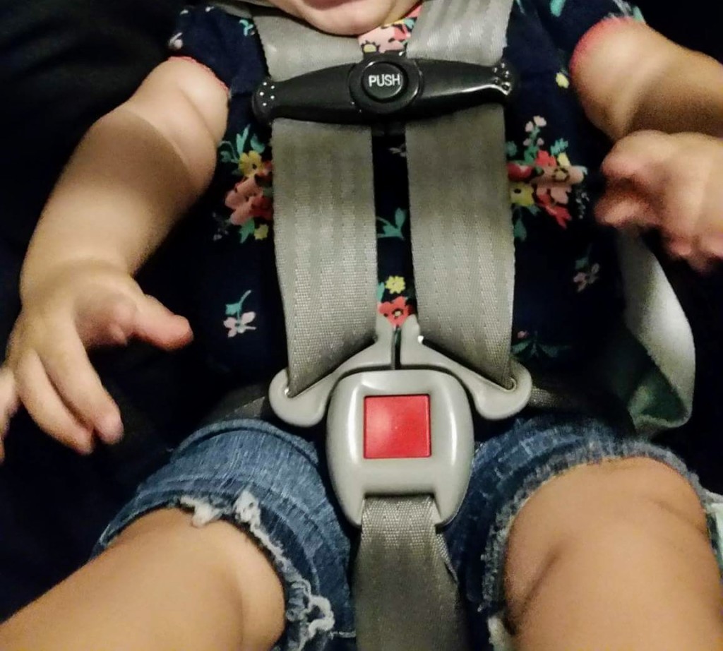 Baby girl safely buckled into an infant car seat.