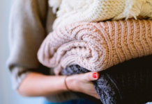 Image: A woman holds of stack of knitted sweaters