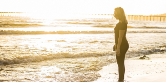 Image: A woman standing on the shoreline, watching the waves