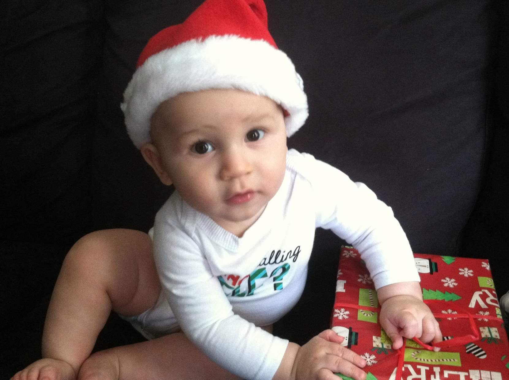 A baby opening a Christmas gift