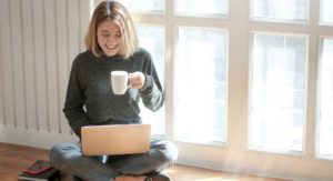 Image: A woman with a cup of coffee and a laptop