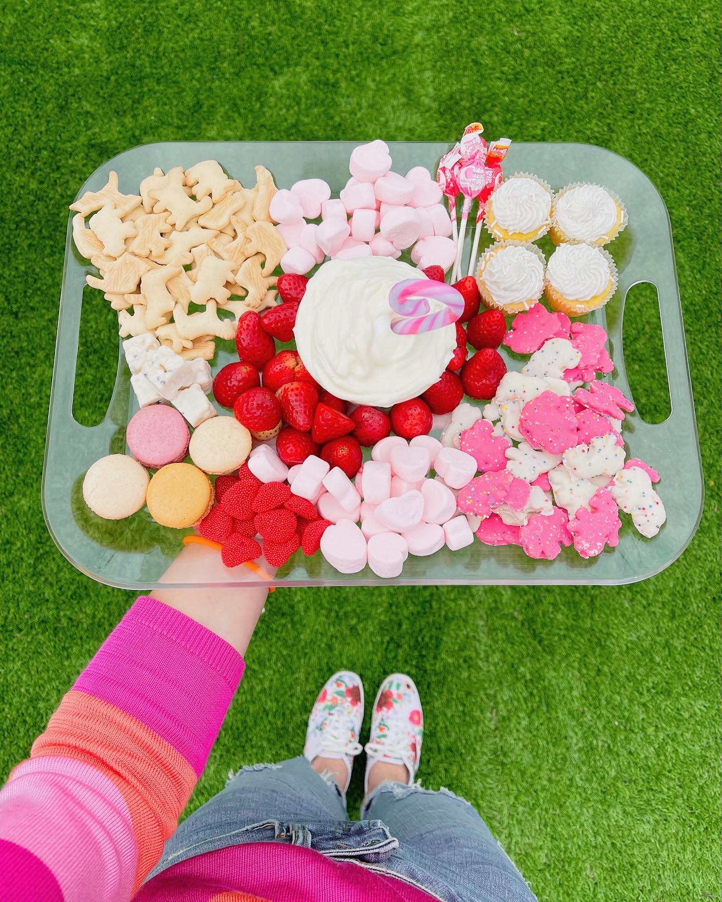 A Valentine's Day themed snack try with animal crackers, marshmallows, macarons, strawberries, and cupcakes