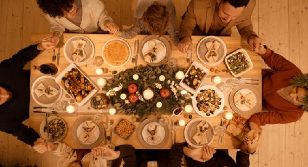 A large family gathered around the dinner table (Family Mealtime is the Heart of the Home Holly Farver Contributor Miami Mom Collective)