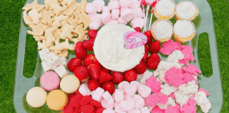 A Valentine's Day themed snack try with animal crackers, marshmallows, macarons, strawberries, and cupcakes