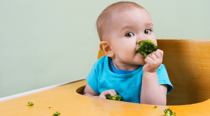 A baby girl trying some solid food (Overcoming My Solid Feeding Fears: A Journey of an Anxious Mom Andrea Wood & Cindy Herde Contributors Miami Mom Collective)