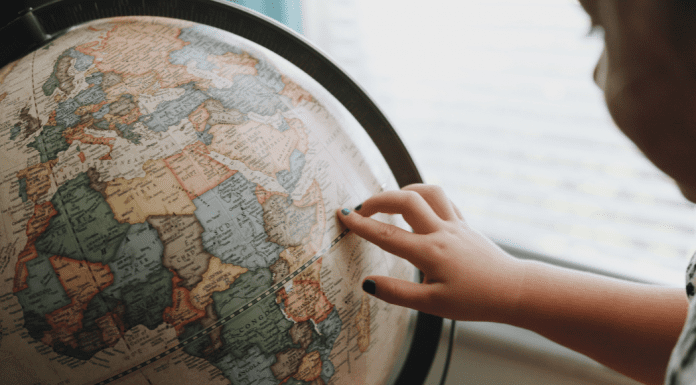 A little girl looking at a globe (Tooth Fairy Traditions From Around The World | Dr. Bob Pediatric Dentist Lynda Lantz Contributor Miami Mom Collective)