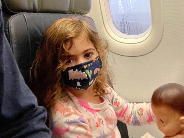 A toddler wearing a mask on an airplane (Wear a Mask: How To Get Your Toddler to Wear One (and Keep It On!) Alexa Gonzalez Contributor Miami Mom Collective)