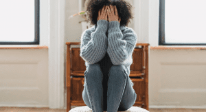 Image: A woman sitting down with her head in her hands (Speak Up: You Matter, Your Opinions Matter Rachelle Haime Contributor Miami Mom Collective)