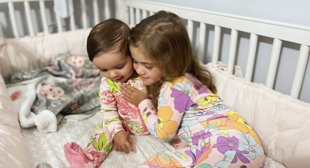 Image: Two sisters snuggling in a crib (A New Roommate and a New Bed (All at Once!): Our Experience Alexa Gonzalez Contributor Miami Mom Collective)