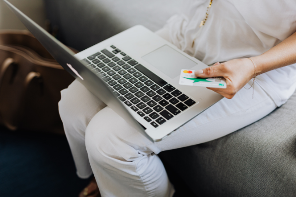 A woman with a laptop on her lap and a credit card in her hand (Bargain Hunting: Money Saving Tips for Online Shopping Ana-Sofia DuLaney Contributor Miami Mom Collective)