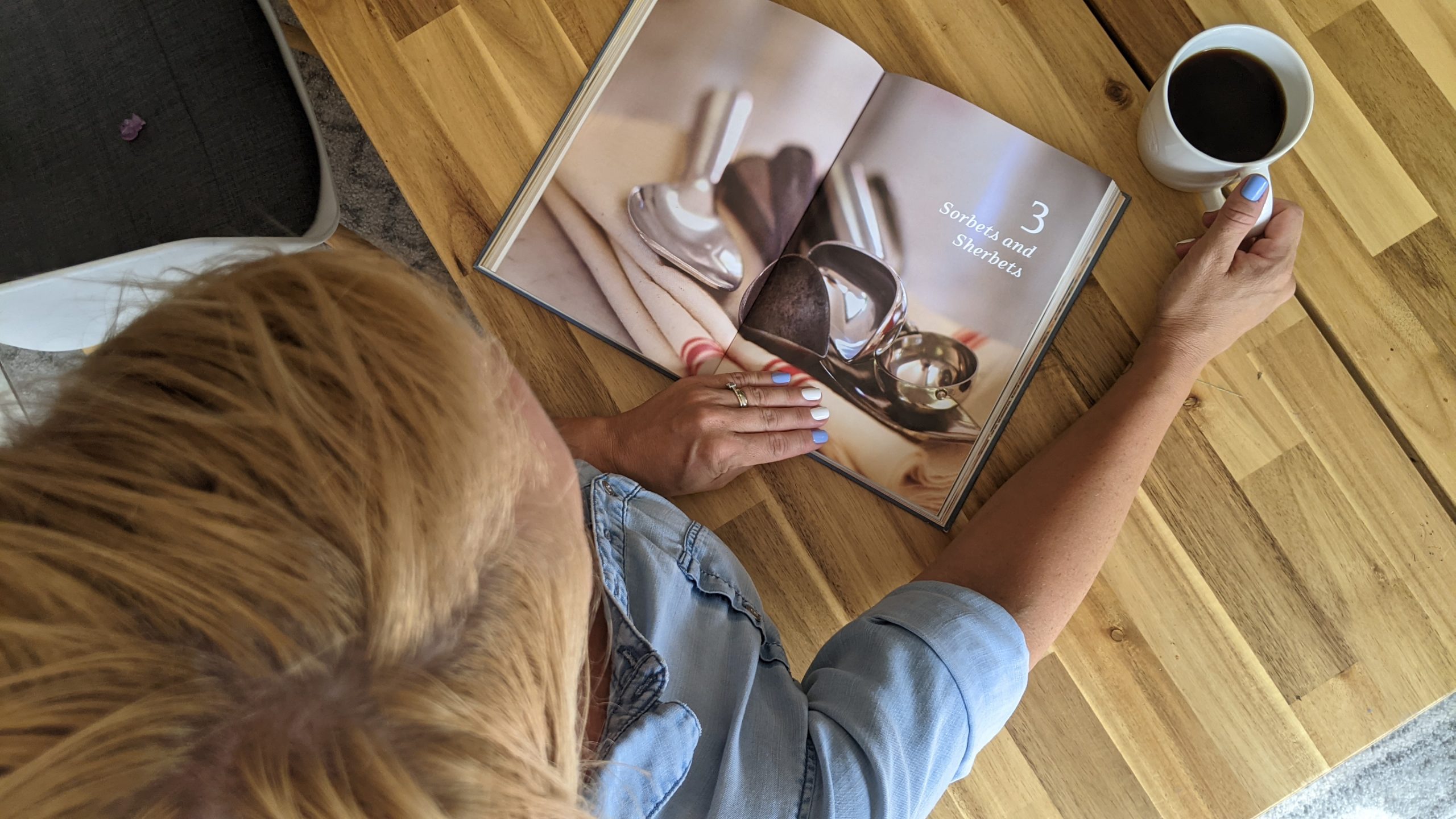 A woman looking at a book about ice cream (July is National Ice Cream Month: Give Me all the Sweetness! Rachel Hulsund Contributor Miami Mom Collective)