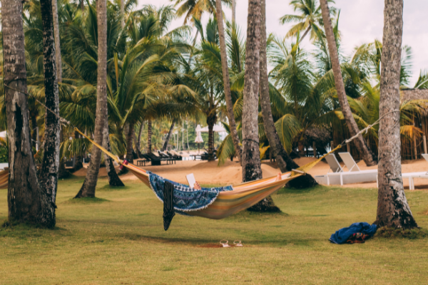 A woman in a hammock reading a book (Summer Reading List for Moms Krystal Giraldo Contributor Miami Mom Collective)