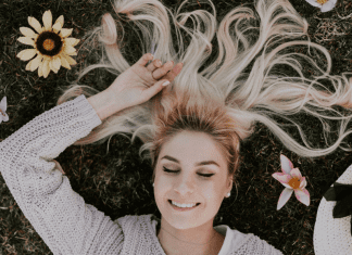 A woman relaxing in field of flowers (National Wellness Month: 6 Easy Ways to Prioritize Your Wellness Today Rachelle Haime Contributor Miami Mom Collective)