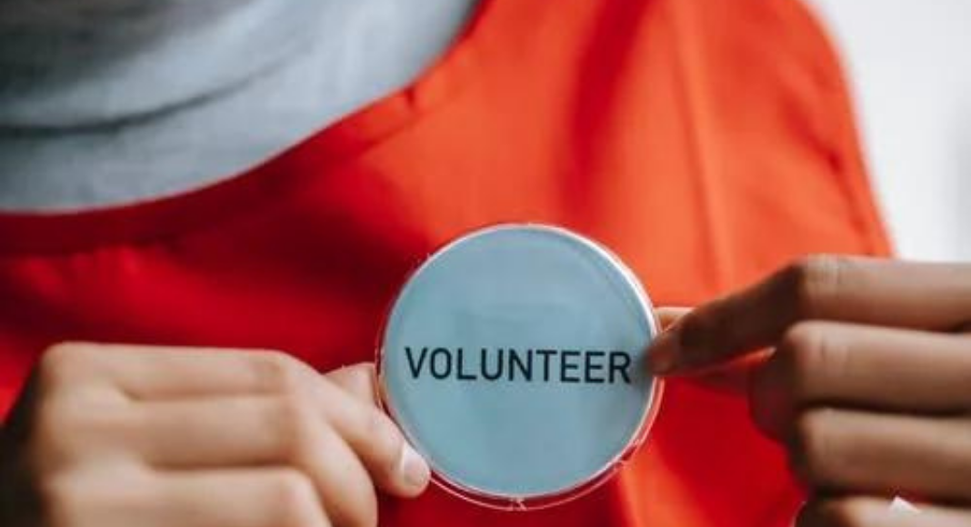 A woman holding a volunteer badge (Your Child Votes YES! Getting Involved at Your Child's School Matters! Holly Farver Contributor Miami Mom Collective)