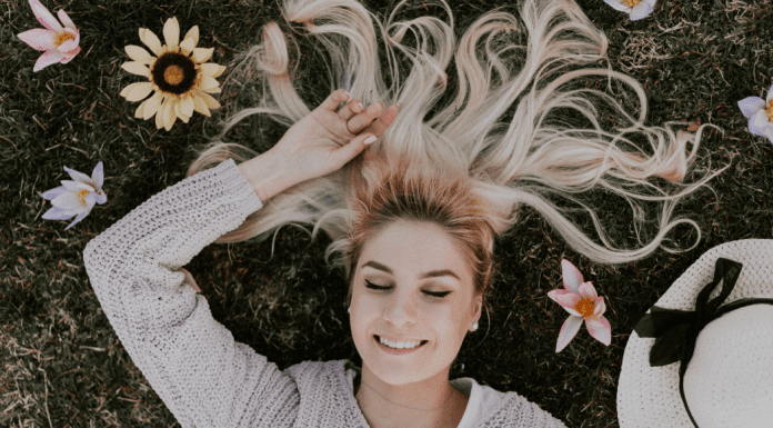 A woman relaxing in field of flowers (National Wellness Month: 6 Easy Ways to Prioritize Your Wellness Today Rachelle Haime Contributor Miami Mom Collective)