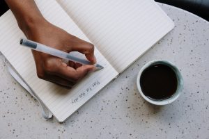 A woman writing in a journal (National Wellness Month: 6 Easy Ways to Prioritize Your Wellness Today Rachelle Haime Contributor Miami Mom Collective)