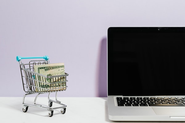 A laptop and a small grocery cart full of cash (Bargain Hunting: Money Saving Tips for Online Shopping Ana-Sofia DuLaney Contributor Miami Mom Collective)
