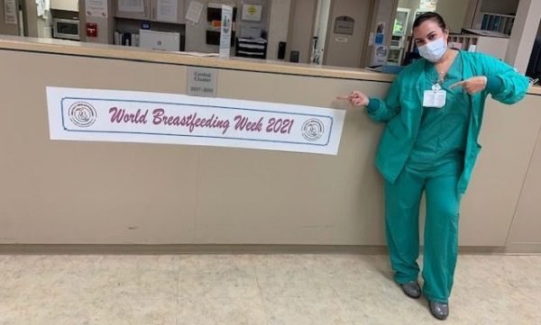 A nurse posing next to a banner for World Breastfeeding Week (World Breastfeeding Week: Raising Global Awareness Alexa Gonzalez Contributor Miami Mom Collective)