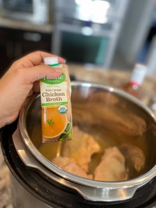 Adding chicken broth to the chicken in the Instant Pot