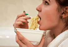 A woman eating a bowl of ramen noodles