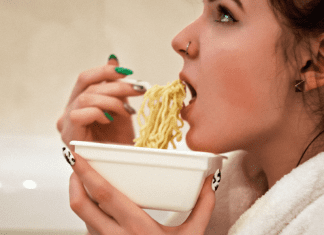 A woman eating a bowl of ramen noodles