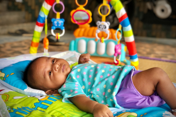 A baby girl lies on her back on a play gym