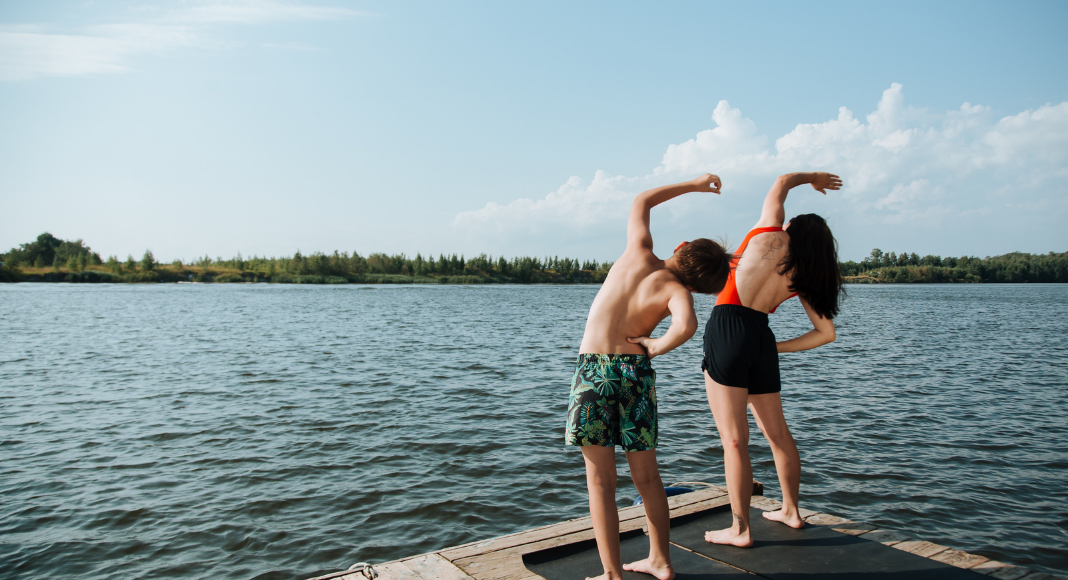 Image: A mom doing yoga with her son by a lake