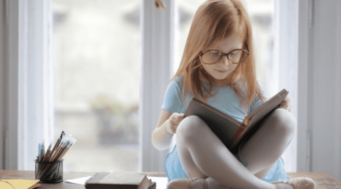 Image: A little girl reading a book (October is Dyslexia Awareness Month Sharonda Stewart Contributor Miami Mom Collective)