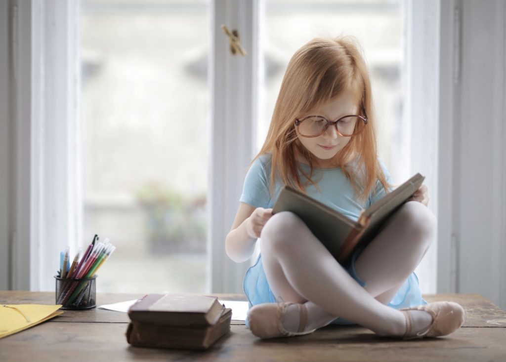 Image: A little girl reading a book (October is Dyslexia Awareness Month Sharonda Stewart Contributor Miami Mom Collective)