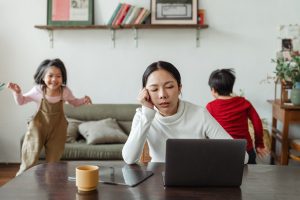 Image: A mom trying to work from home while her kids play in the background (5 Tips to Manage Stress through Motherhood Zoe Costa Contributor Miami Mom Collective)