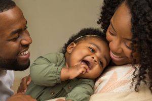 Image: A mom and dad smiling at their baby (Brittany Aquart Contributor Miami Mom Collective)