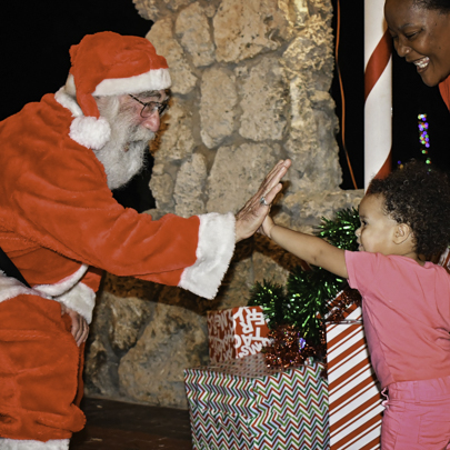 Image: A little boy giving Santa a high five (The Ultimate Guide to 2021 Miami Area Holiday Events & Activities Presented by Pinecrest Gardens Lynda Lantz Editor Miami Mom Collective)