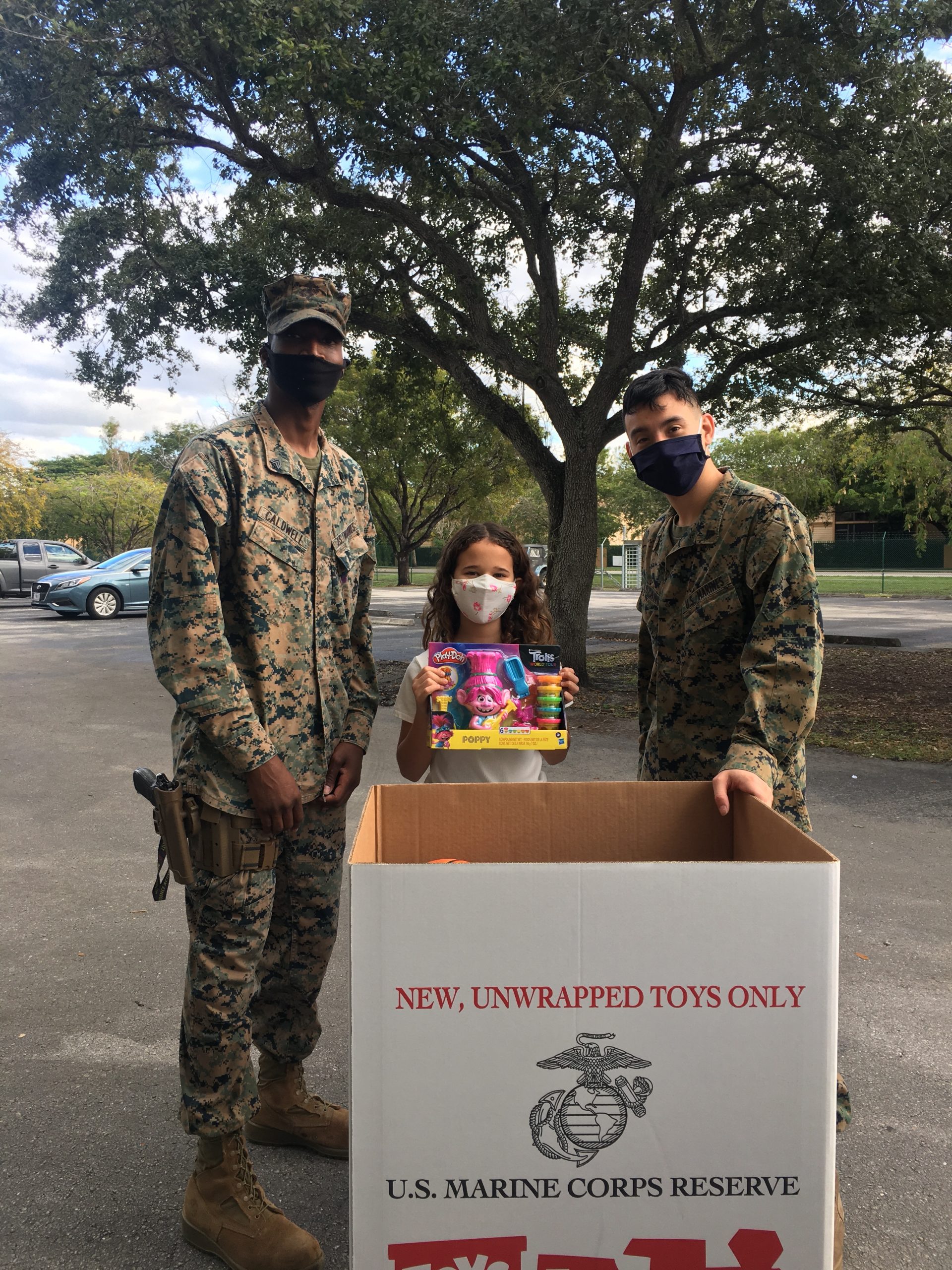 Image: Adita's daughter collecting toys for Toys for Tots with 2 US Marines (Toys for Tots: Making a Difference for America's Children Adita Lang Contributor Miami Mom Collective)