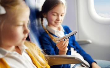 Image: Two girls sitting together on an airplane (Holiday Travel: The Ultimate Prep List for Smooth Family Travel Vanessa Santamaria Contributor Miami Mom Collective)