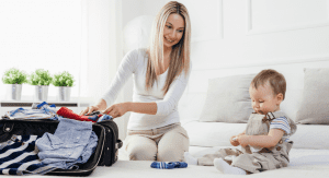 Image: A mother packing a suitcase with her infant (Holiday Travel: The Ultimate Prep List for Smooth Family Travel Vanessa Santamaria Contributor Miami Mom Collective)