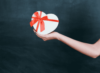 Image: An outstretched arm holding a gift box (Teacher Gifts: Thoughtful Ideas For Every Budget Lorena Lougedo Contributor Miami Mom Collective)