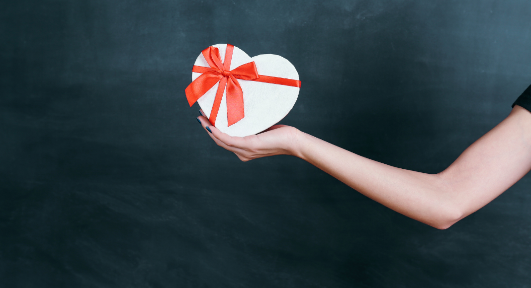 Image: An outstretched arm holding a gift box (Teacher Gifts: Thoughtful Ideas For Every Budget Lorena Lougedo Contributor Miami Mom Collective)