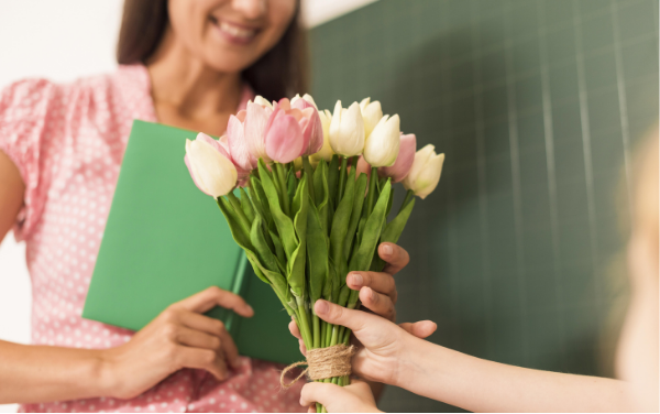Image: A student handing a teacher a bouquet of flowers (Teacher Gifts: Thoughtful Ideas For Every Budget Lorena Lougedo Contributor Miami Mom Collective)