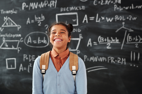 Image: A child smiling in front of a blackboard (Krystal Giraldo Contributor Miami Mom Collective)