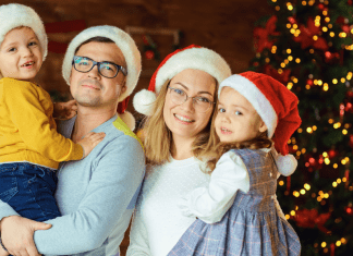 Image; A family wearing Santa hats and standing in front of a Christmas tree (Healthy Holidays: A Survival Guide | Part 2 Dina Garcia Contributor Miami Mom Collective)