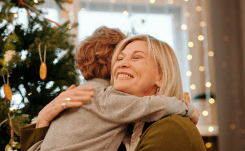 Image: A grandmother hugging her grandson at Christmas (Holiday Travel and Gatherings: Protecting Your Family From COVID & Flu Lynda Lantz Editor Miami Mom Collective)