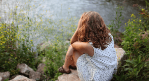 Image: A woman sits beside a lake (Toxic Positivity: How to Stay True to Yourself Bella Behar Contributor Miami Mom Collective)