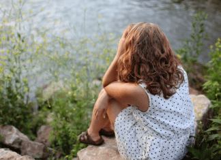 Image: A woman sits beside a lake (Toxic Positivity: How to Stay True to Yourself Bella Behar Contributor Miami Mom Collective)