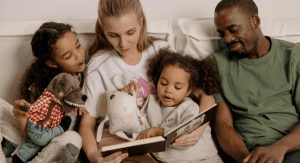 Image: A multi-racial family sitting a reading a book together