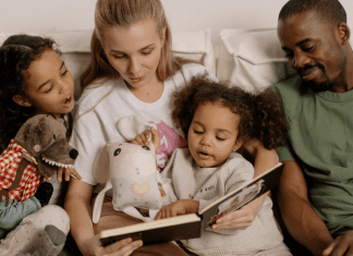 Image: A multi-racial family sitting a reading a book together (Children's Books For Black History Month Kristen Llorca Contributor Miami Mom Collective)