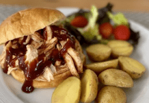 A BBQ pulled chicken sandwich, served with roasted potatoes and salad