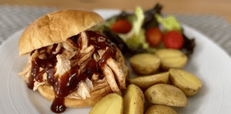 A BBQ pulled chicken sandwich, served with roasted potatoes and salad