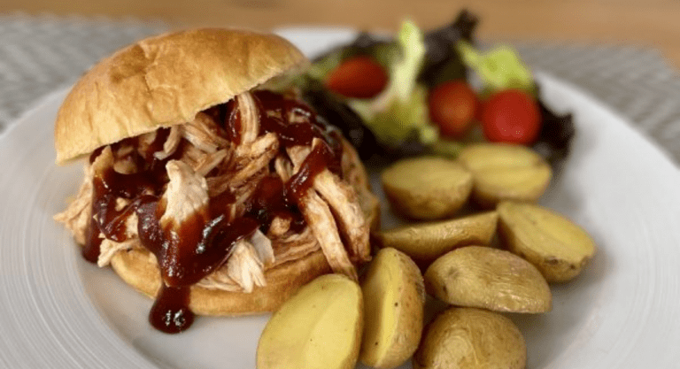 A BBQ pulled chicken sandwich, served with roasted potatoes and salad