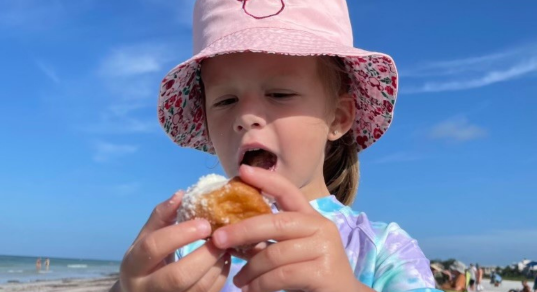 A little girl enjoys a donut from Meaney's Mini Donuts