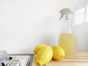 A few lemons next to a spray bottle of lemon juice on a kitchen counter